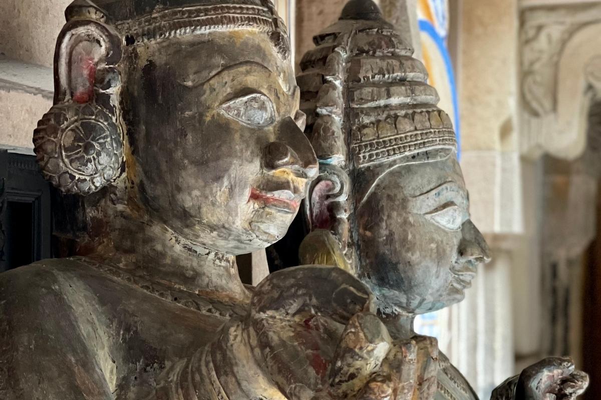 Two stone Hindu statues in Varanasi. The background is white stone with a small section painted blue, yellow, and gold.