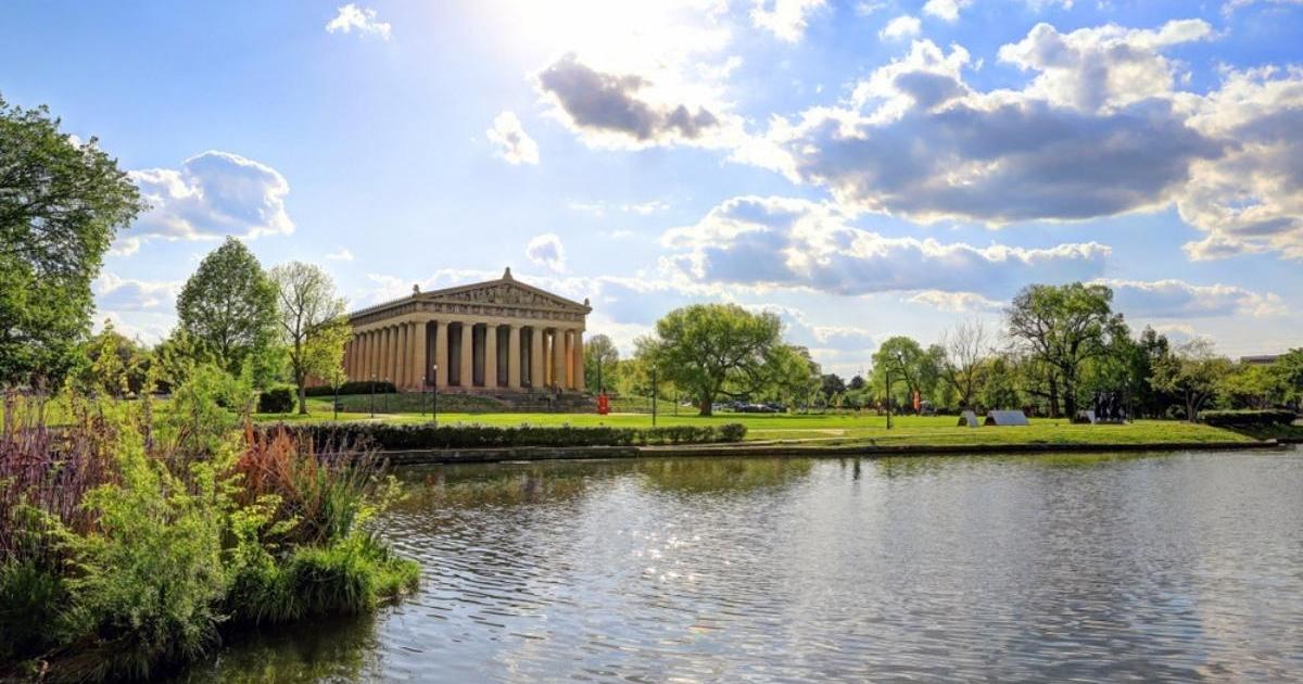 Nashville Parthenon in green park with trees, water, and sunny blue sky with white clouds