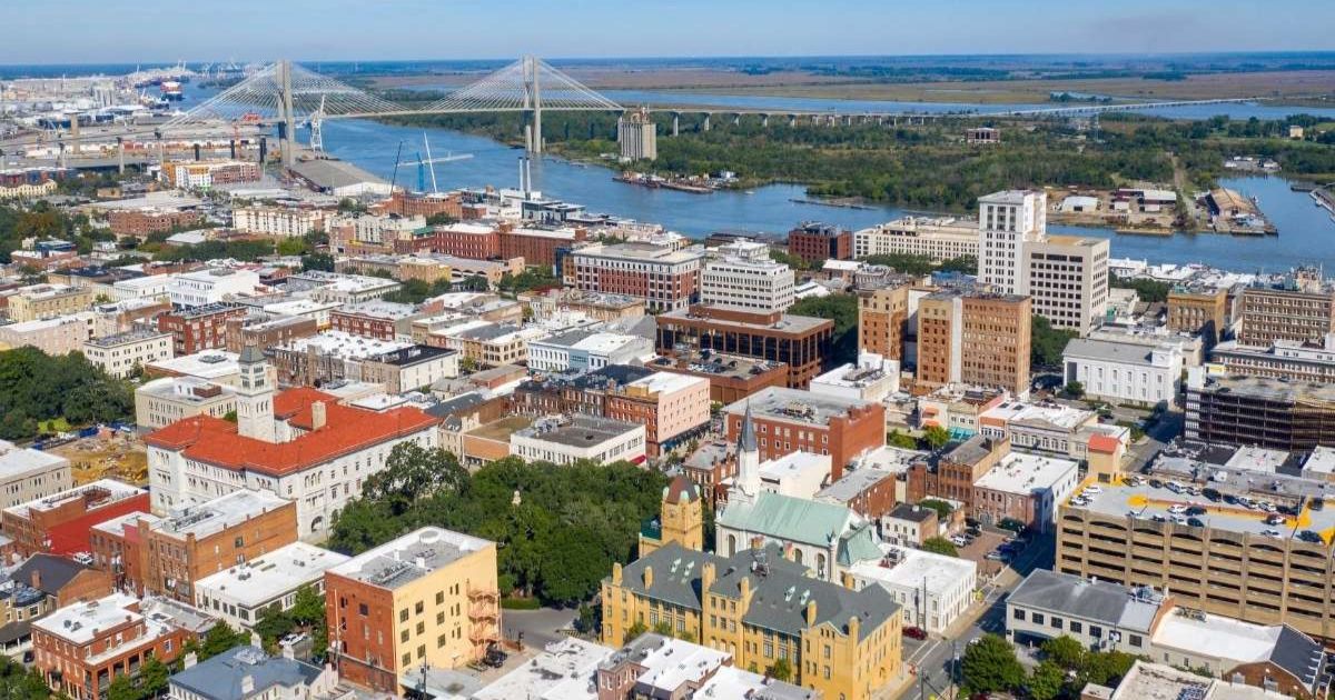 Aerial view of buildings, trees, bridge and river in downtown Savannah